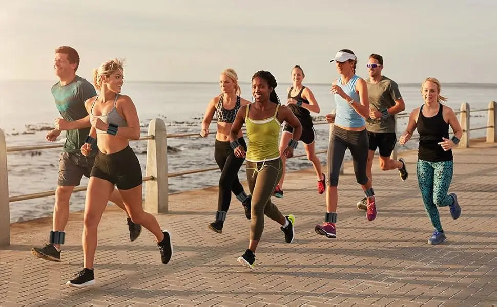 Group of runners wearing Wearable Wrist &amp; Ankle Weight Bangles along a scenic waterfront path.