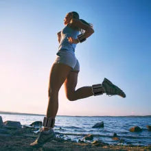 Woman running by the water wearing Wearable Wrist &amp; Ankle Weight Bangles for enhanced workout performance.